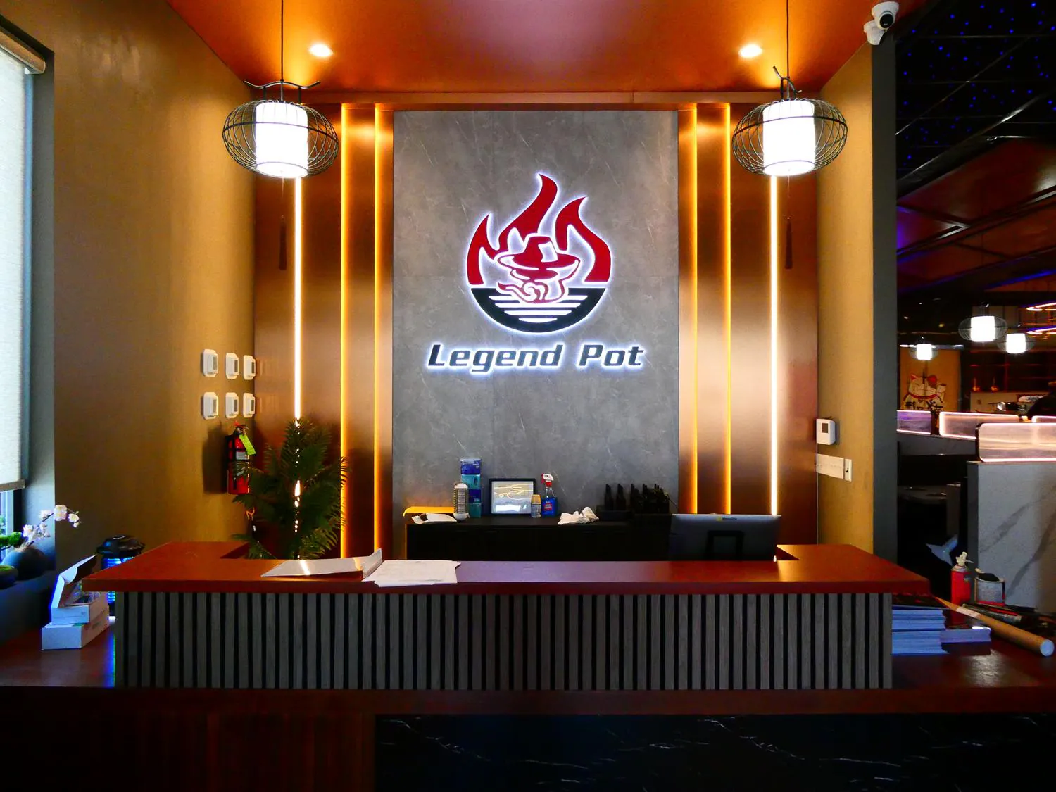 Legend-Pot-Hot-Pot-Restaurant-Baton-Rouge The reception desk at Legend Pot, featuring its illuminated logo on a stone wall with warm ambient lighting.